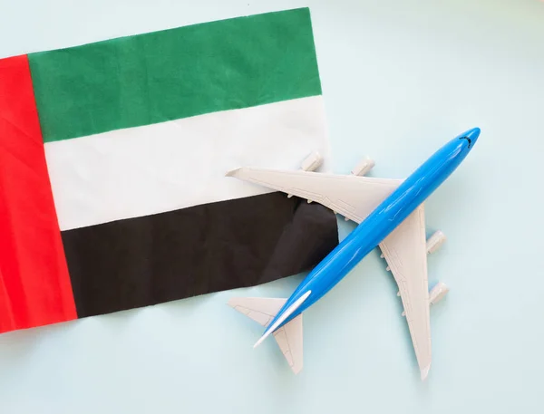 Top view Passenger blue plane flying over the flag of the United Arab Emirates. The concept of tourism and travel around the world. Flying plane in men\'s