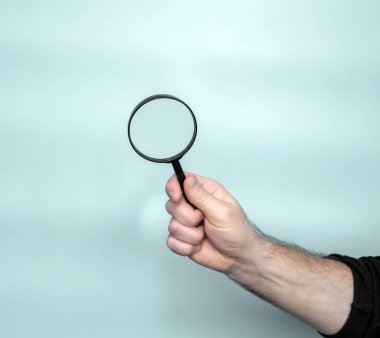 A magnifying magnifying glass in a man's hand is a man, an object in a man's hand is glass for poor eyesight.