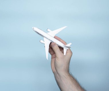 Travel concept model of a passenger plane in a man's hand, a white plane in a man's hand on a blue background. Space copy. Airplane flight simulation.