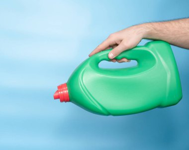 Liquid powder in a green plastic bottle in a man's hand copy space. Background with laundry detergent bottle. Chemistry bottle