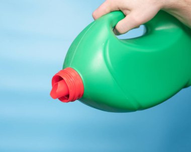 Liquid powder in a green plastic bottle in a man's hand copy space. Background with laundry detergent bottle. cleaning Chemicals bottle