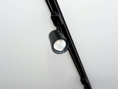 Background Led track lamp on the ceiling in the interior. Interior spotlight in black color. Modern track lamp with a lot of swivel lamps. The concept of lighting in the house.