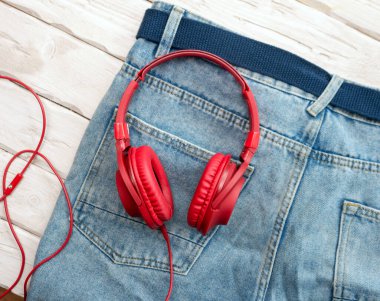 The concept of listening to music, on jeans are red overhead music headphones modern.