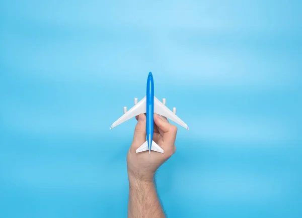 Background imitation of a flight of a passenger plane by a human hand on a blue background copy space.