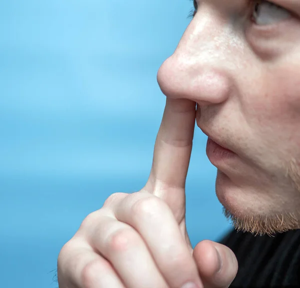 The man picks his nose. Close-up of a man with a finger in his nose.