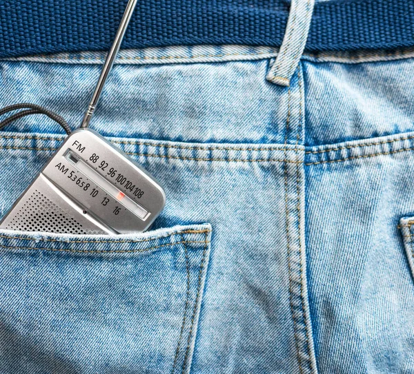 Top view of a radio in a pants jeans pocket. The concept of listening to radio waves of music or news. Portable radio receiver