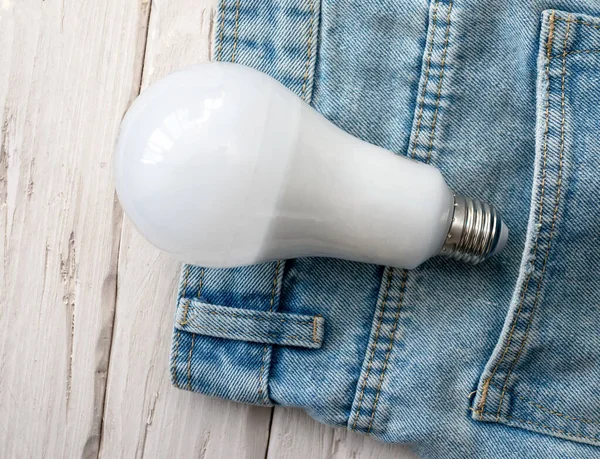 Top view Electric light bulb in pants pocket. Electrical concept. Energy saving lamp with white lamp bottle.
