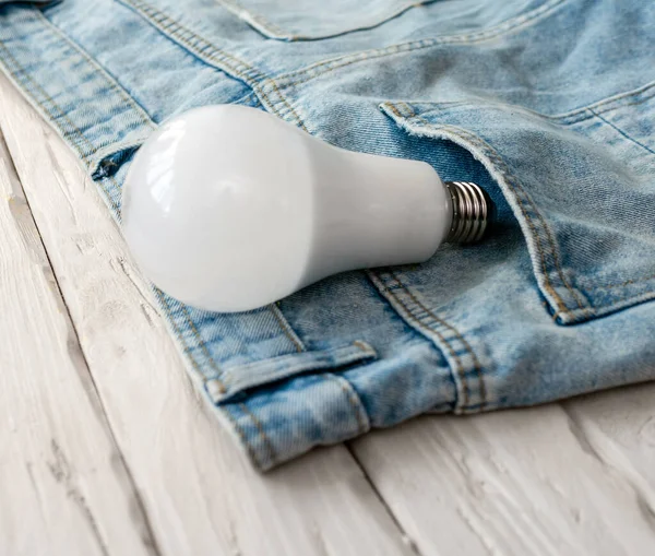 An electric light bulb in a pants pocket. Electrical concept. Energy saving lamp with white lamp bottle.