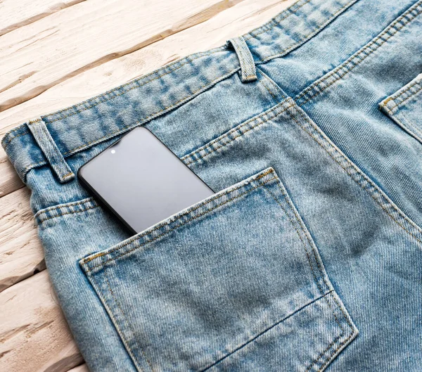 Top view smartphone in denim pants pocket. Phone in blue jeans pocket. Mobile phone gadget concept.