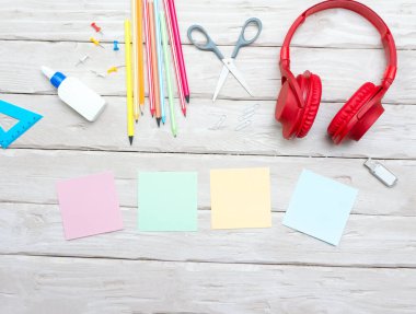 Top view musical overhead headphones with colorful stickers for text. Home office with pencils. Scissors. Copy space. Office. Desktop. Online education. Workplace background.