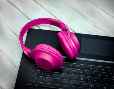 Background red Musical headphones on a black laptop. Audio headphones for listening to music. Desktop. Online education. Home Office.