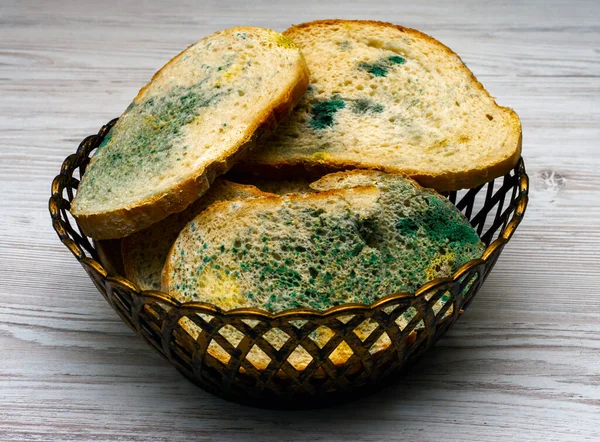 Close-up, Homemade bread with mold in a grocery basket, on a light wooden table in the kitchen, harmful bread with fungus, food poisoning, microbes. Flowered bread.