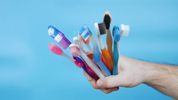 Different Toothbrushes Man Hand Blue Background Set Multi Colored Toothbrushes — Stok video