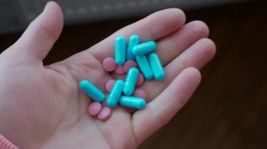 Medical capsules in a person's hand, blue capsules for the treatment of diseases. Pills, antidepressants or antibiotic in a man's hand