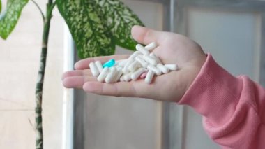 Throw medical pills with capsules on the floor. A man's hand holds a lot of medicinal tablets in his hand. The concept of treatment with pharmaceutical drugs