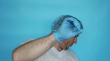 Sad doctor says no. Sad doctor pointing the prohibition gesture. A man in a medical gown, in a medical cap and sterile rubber gloves, pointing a stop hand gesture