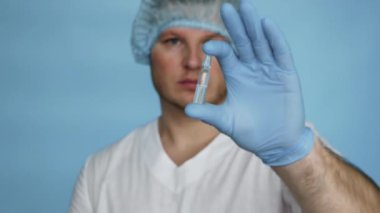 Doctor in a dressing gown demonstrates the medicine in a medical ampoule. Treatment liquid medicine in an ampoule. Male worker pharmacist