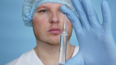 In slow motion A doctor in a dressing gown in sterile mittens demonstrates the medicine in an ampoule. Treatment liquid medicine in an ampoule. Male worker pharmacist