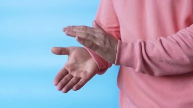 Mavi arka planda ellerini çırp. Ağır çekimde alkış. Pembe kapüşonlu bir adam alkışlıyor..