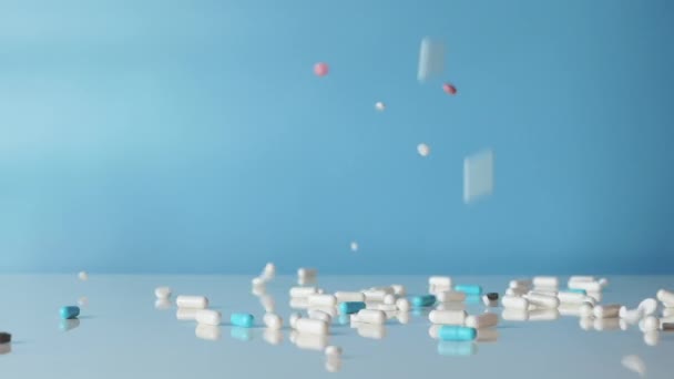 Kapsułki Medyczne Spadają Zwolnionym Tempie Białym Stole Niebieskim Tle Tabletki — Wideo stockowe