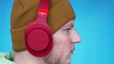 Portre Genç üzgün adam mp3 dinliyor. Mavi arka plandaki şık genç adam fotokopi kulaklığı takıyor.