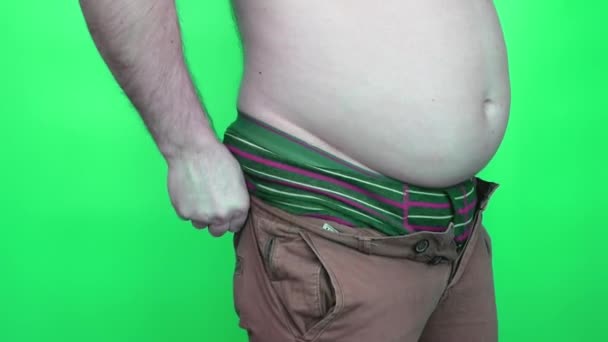 Товстий Молодий Чоловік Намагається Одягнути Джинсові Штани Зелений Фон Чоловік — стокове відео