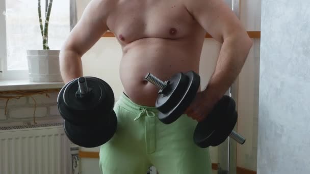 鏡の前にポーズをとっているジムでダンベルを持つ太った男 男は体の筋肉を見て 脂肪1と面白いビデオ 肥満の人 — ストック動画