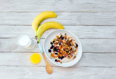 Kulak meyveli bir kasede yulaf lapası, bir bardak süt, sütlü yulaf lapası, kurutulmuş meyveli diyet kahvaltı, kurutulmuş kayısı ve taze muzlu fındık ve ballı müsli..