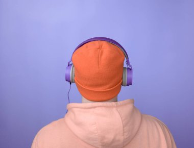 Tarz sahibi bir adamla müzik geçmişi. Turuncu şapkalı ve mor kulaklıklı kapüşonlu yakışıklı bir genç. Kameraya arkası dönükken stüdyoda müzik dinleyen bir adam..