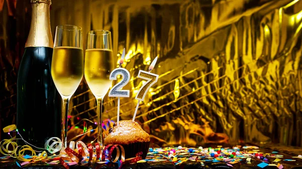 stock image Copy space solemn background. Happy birthday golden background with number  27. Greeting card or postcard with a bottle of champagne with poured champagne in glasses.