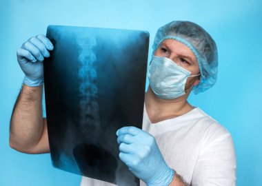 Doktor cerrah, doktorun ellerindeki omurga röntgeninin insan omurgasındaki hasarını analiz eder. Omurgalı doktor geldi. Doktor ortopedist-travmatolog yaşlı bir insanın omurgasında osteokondrosis tedavisi teşhisi.