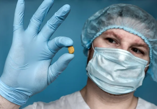 Removed Stone 14 mm from the kidney, in the doctor\'s hands. Human urolithiasis. Phosphate or oxalate kidney stone. Urologist surgeon demonstrates a kidney stone. Doctor in medical uniform.