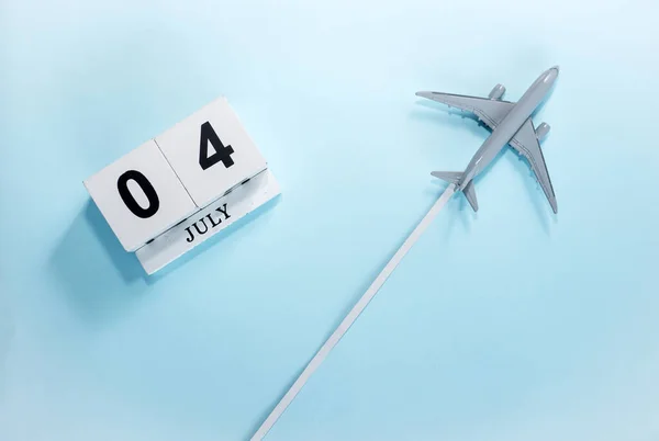 7月4号的日历带着飞行客机的日历的顶部视图 时间安排 旅行概念 复制空间 — 图库照片