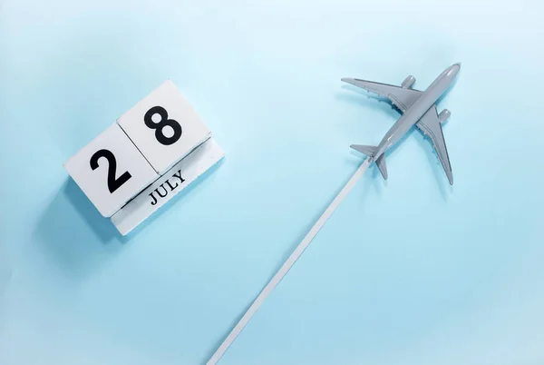 七月历二十八号带着飞行客机的日历的顶部视图 时间安排 旅行概念 复制空间 — 图库照片