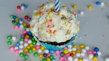 Üst manzara, yanan bir mumla dönen konfeti pudingi. Çöreğin üzerinde şenlikli puding. Doğum günün kutlu olsun. Tatil için tebrikler. Boşluğu kopyala