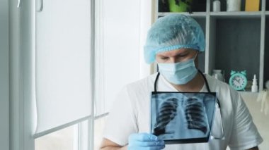 Doktor ofiste, radyograf hastanedeki akciğerlerin röntgenini inceliyor. Doktor zatürree teşhisi koydu. Bir erkek doktorun ellerinde röntgen..