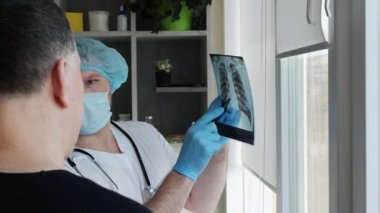 Doktor, hastayla birlikte ofiste hastaya danışıyor. Radyolog, yaşlı bir insanın akciğerlerinin röntgenini inceliyor. Doktor zatürree teşhisi koydu.