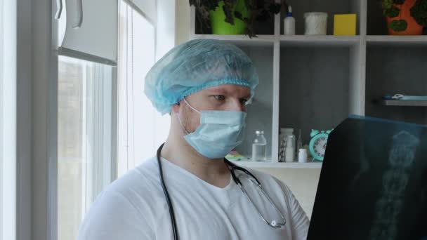 医者は病院の人の背中のX線を見て患者に診断を下す 医師の手の中に人間の背骨のX線 病院での治療の概念 — ストック動画