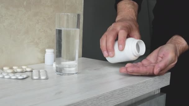 一位老人将一剂医用胶囊药物倒入他的手中 并倒入一杯水 处方药的概念 一个手里拿着药丸的老人喝健康药丸 — 图库视频影像