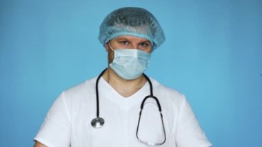 Yeşil posteri olan doktor mesaj için boş. Pankart bir sağlık çalışanının elinde. Uzayı kopyala Maskeli bir steteskop ve mavi arka planda steril kapaklı bir doktor..