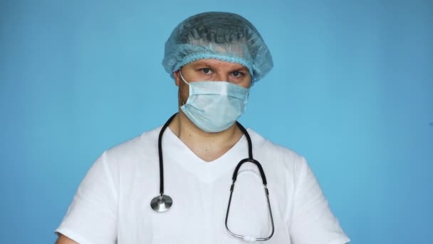 テキストのための空の緑色のポスターを持つ医師 医療従事者の手にバナー コピースペース マスクの聴診器と青い背景の滅菌キャップと一致する医者 — ストック動画