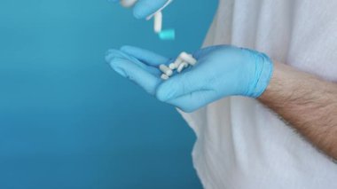 Elindeki doktorun elinde ilaç kapsülleri vardı. Şişeden elinize farmakolojik haplar dökün. Hastalıkların tedavisi için ilaç içeren bir eldiven verin.