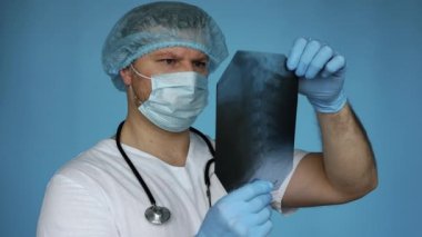 Hastane üniformalı bir travmatolog, bir insanın omurgasının röntgenini analiz eder. Omurga hastalıkları, osteokondroz tanısı ve terapisi. Hastanedeki doktor sırt hastalığı teşhisi koydu.
