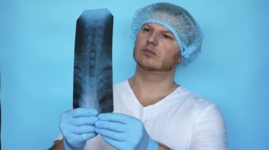 Doktor, hastanede çekilen röntgende insan omurgasıyla ilgili bir sorun teşhis etti. Hastanedeki bir tıp çalışanı omurga eğriliğinin röntgenini analiz ediyor. Tıp üniformalı doktor.