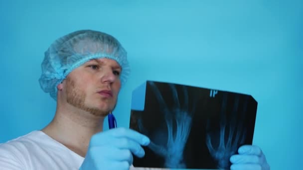 手に男性医師の手首のX線 医者は事務所のX線で人の指の怪我を分析する 病院で手首のX線と外傷学者 — ストック動画