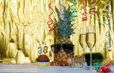 Gözlüklü neşeli ananas... 38 numaralı neşeli doğum günü karakteri. Altın bir arka plan ve şampanya kadehleri için harika bir arka plan. Yıldönümünüz kutlu olsun. 