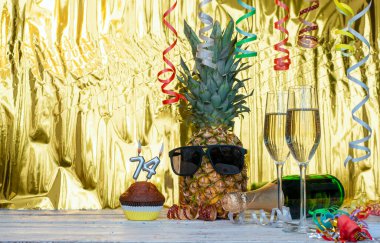 Gözlüklü neşeli ananas... 74 numaralı neşeli doğum günü karakteri. Altın bir arka plan ve şampanya kadehleri için harika bir arka plan. Yıldönümünüz kutlu olsun. 