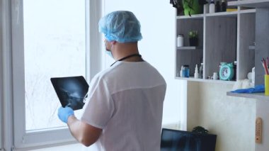  Beyin cerrahı hastanedeki bir ofiste insan kafatasını analiz ediyor. Bir doktorun elinde insan beyninin röntgeni var. Doktor, sinir sistemindeki kafatası yaralanmalarını, hastalıkları ve yaraları analiz ediyor..