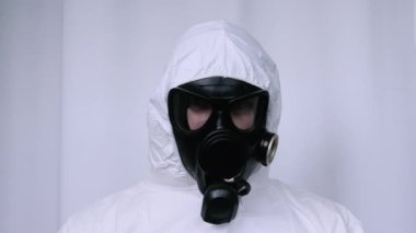 Gaz maskeli bir adamın portresi. Radyasyona maruz kalma riski. Beyaz tulumlu, kimyasal koruma altında bir adam. Kimyasal radyasyon kirliliği. Çevresel kirlilik