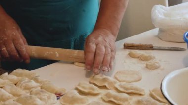 Bir kadın hamurdan hamur köftesi ve krep heykeli yapıyor, mutfakta buğday unundan, yaşam tarzından yemek pişiriyor. Hamur köftesi heykeli. Ev yemeği konsepti.